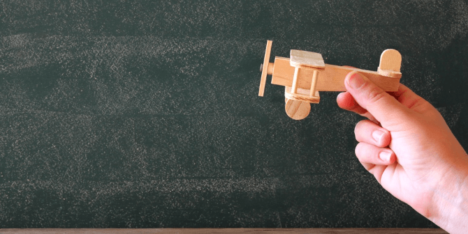 a hand holding a small wooden model of a plane