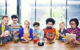 a group of people sitting at a table looking at a devices