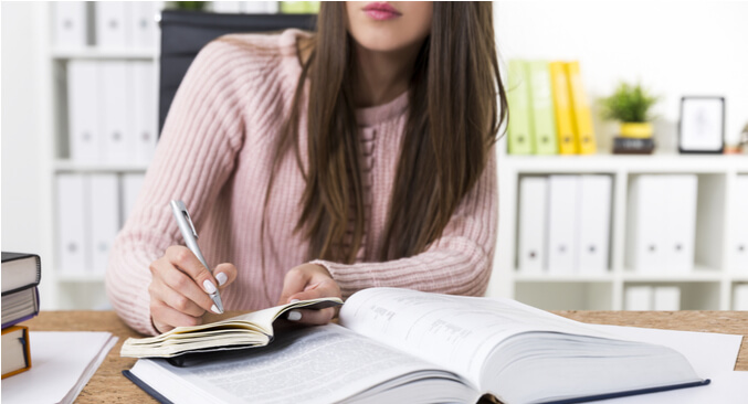 a person writing on a piece of notebook