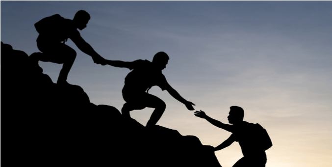 hikers helping each other up a steep hill