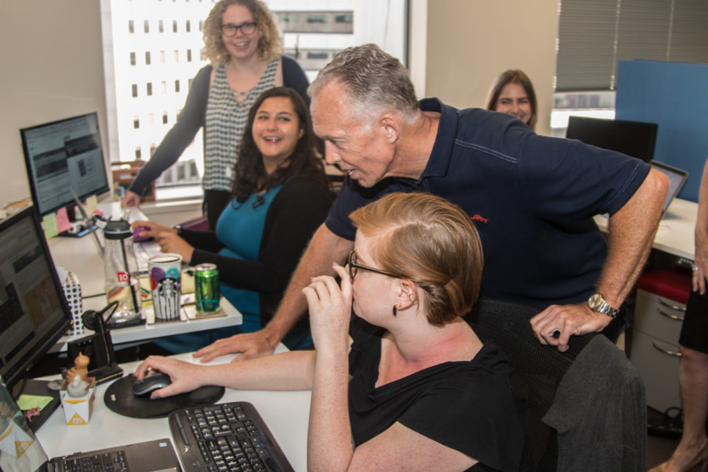 a group of people sitting around a computer