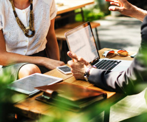 a group of people sitting at a table with laptops