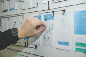 person pushing a pin into a posterboard