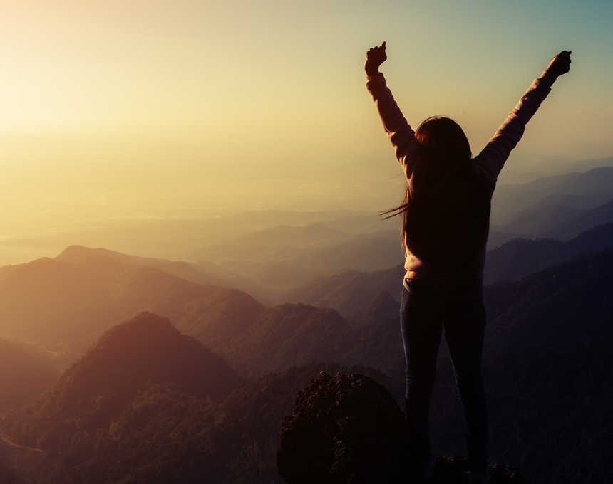 a person standing on a hill with arms raised