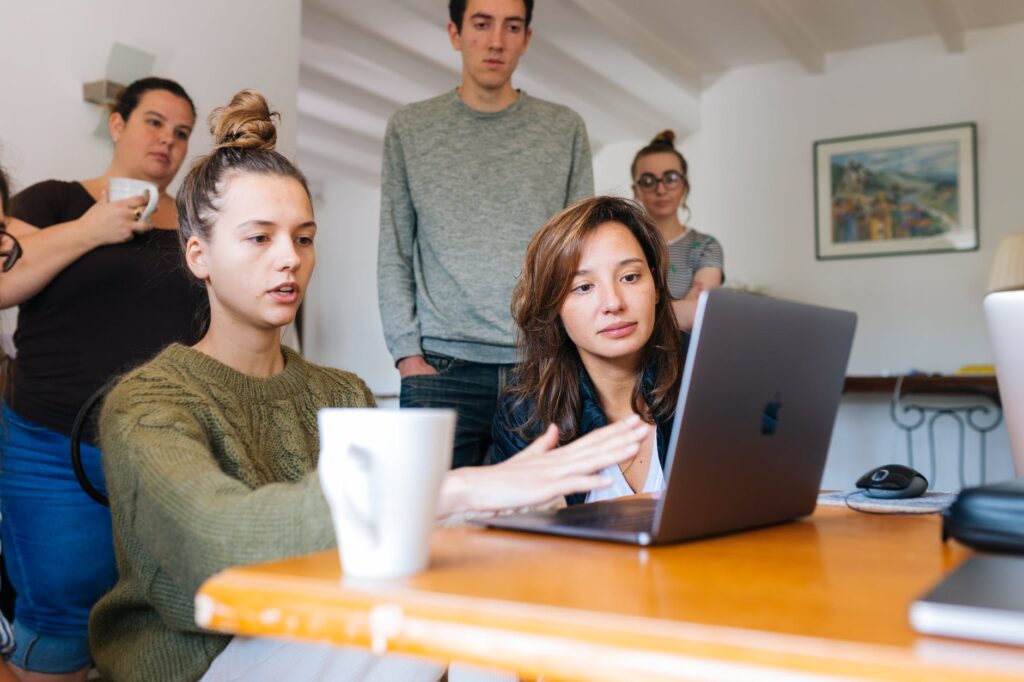 a group of people sitting around a table with a laptop