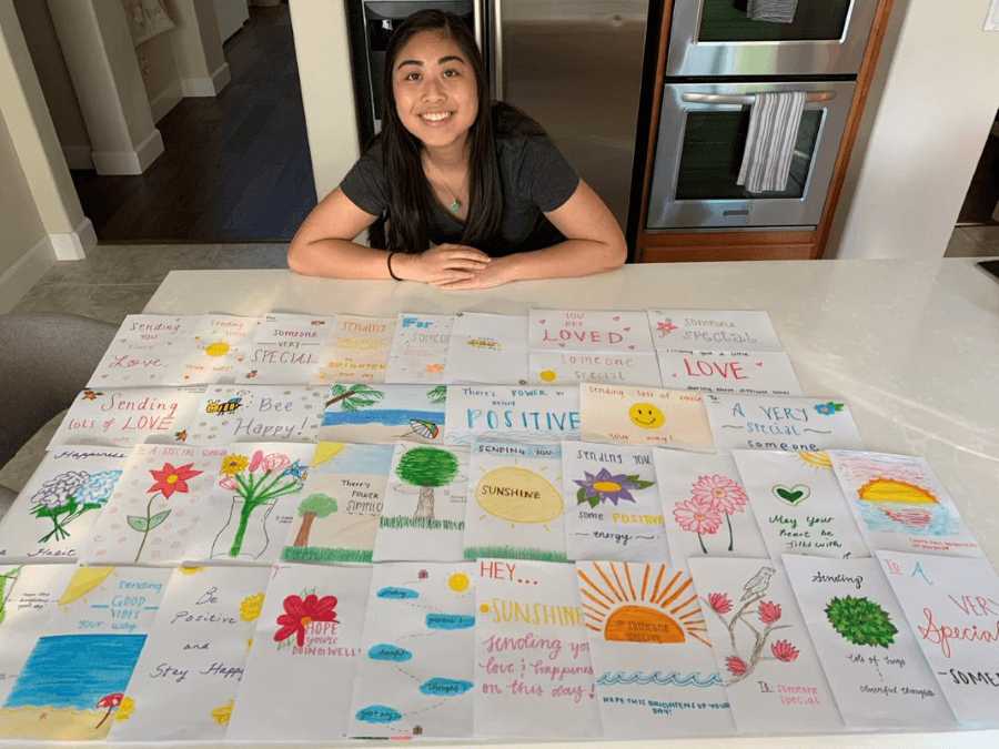 a person sitting at a table with a large pile of home made cards